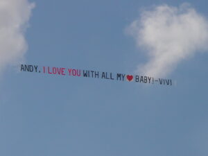 Aerial letter banner trailing a plane through the sky spelling out a special, personalized "I love you" message.