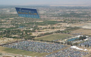 Large Aerial billboard flying high over a crowded parking lot at Coachella Music festival, displaying an advertisement for Encore Beach Club.