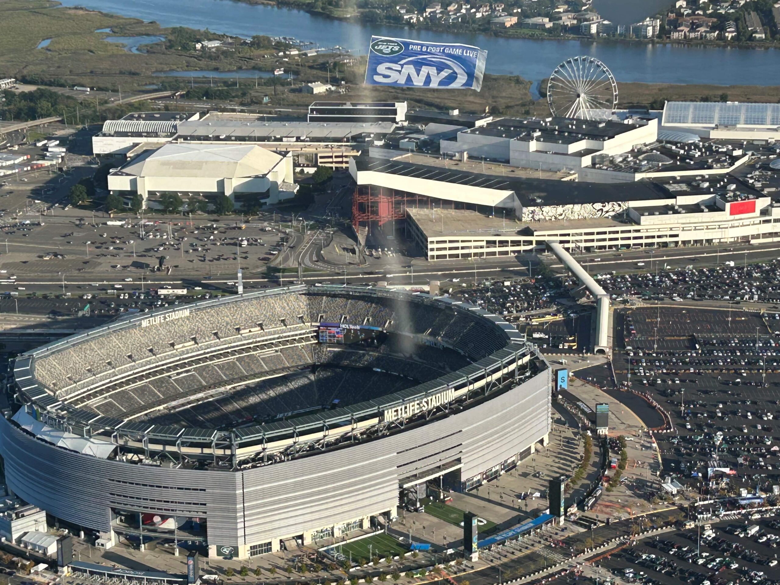 Aerial image of a plane towing a banner advertisement over Metlife Stadium during a football game.